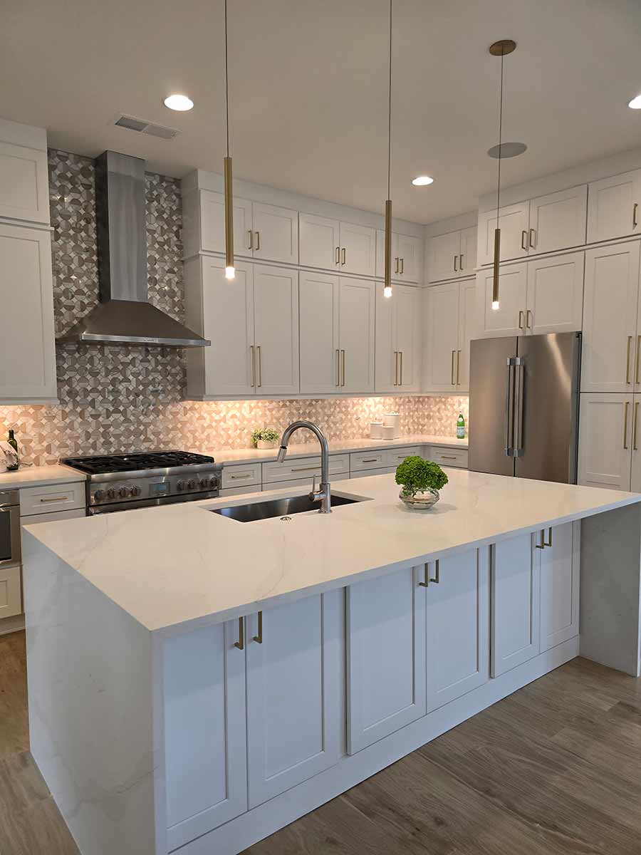 White shaker kitchen with gold hardware and waterfall quartz island